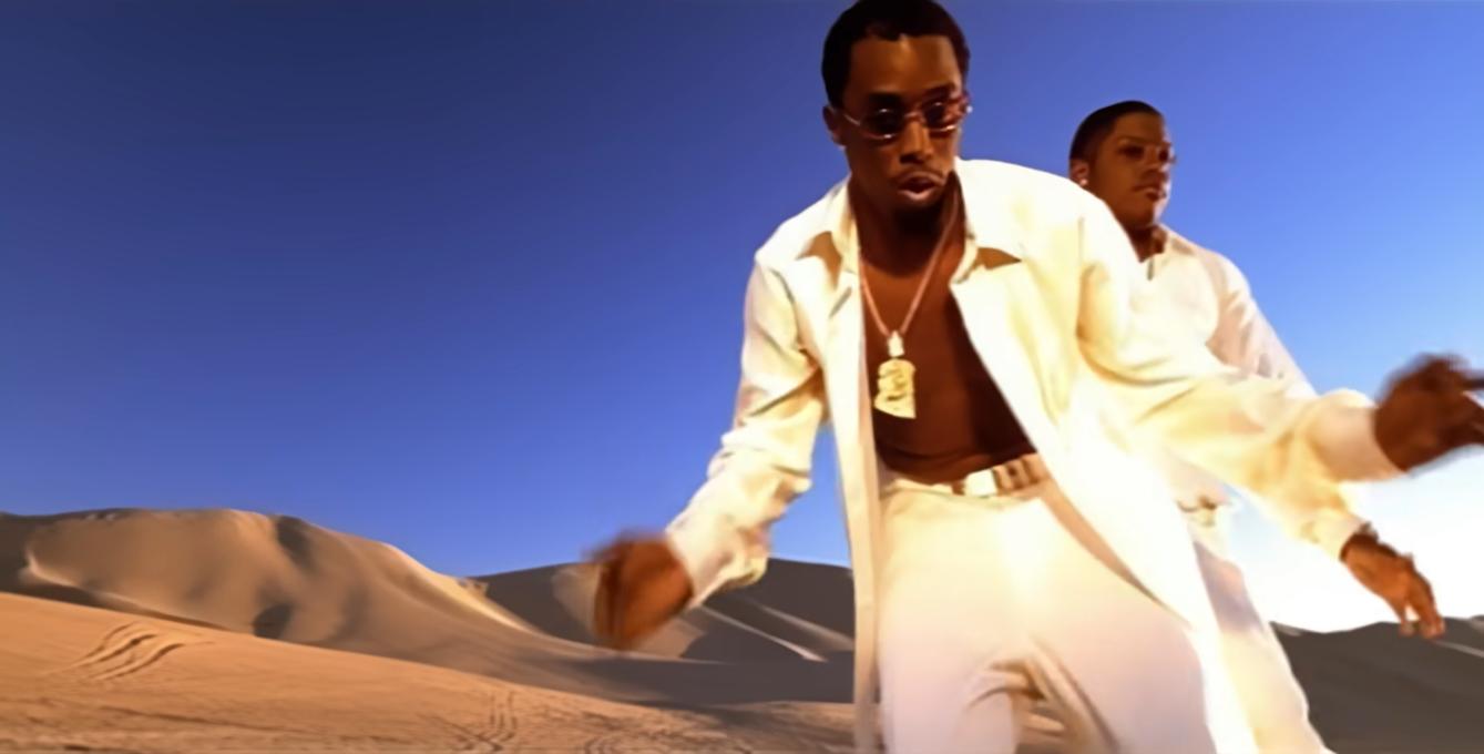 A picture of a music video with two men in a desert